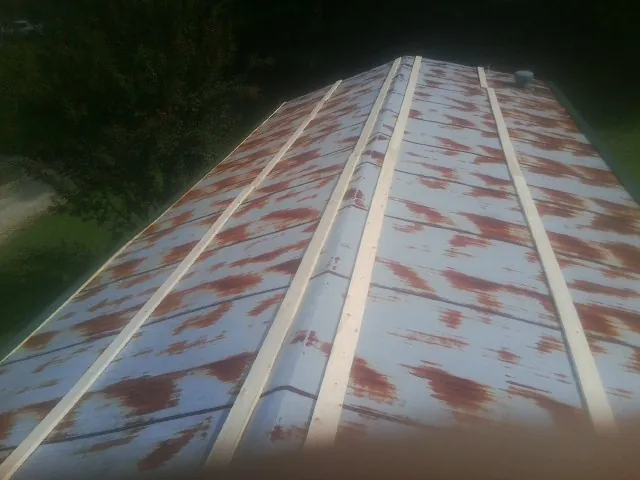 Rusted metal roof panels with new wood purlins before replacement — Storm Damage Roof Repair in Belle Center by Roofing Brothers