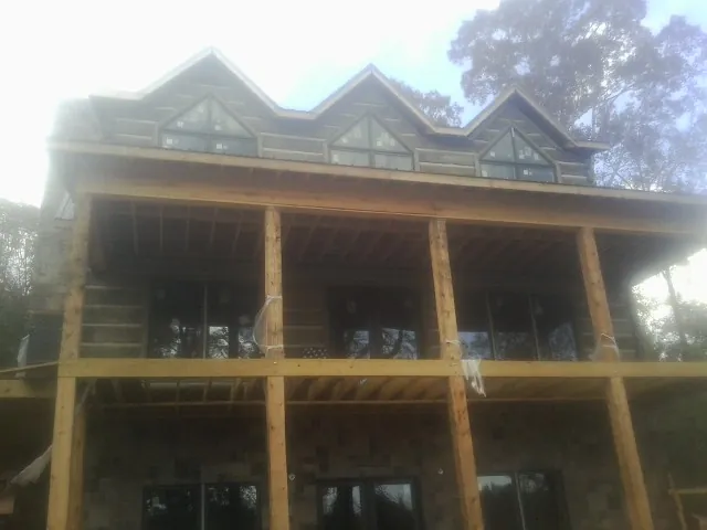 Dormers and porch framing on a large log home under construction — Roof Coating work by our crew in Belle Center