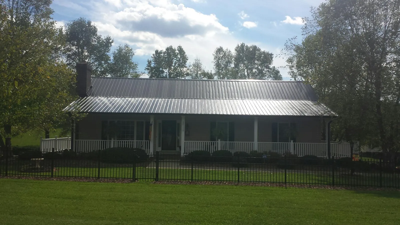 Gray metal roof on a brick ranch with a full width front porch — Gutter Guard Installation work by our crew in Belle Center
