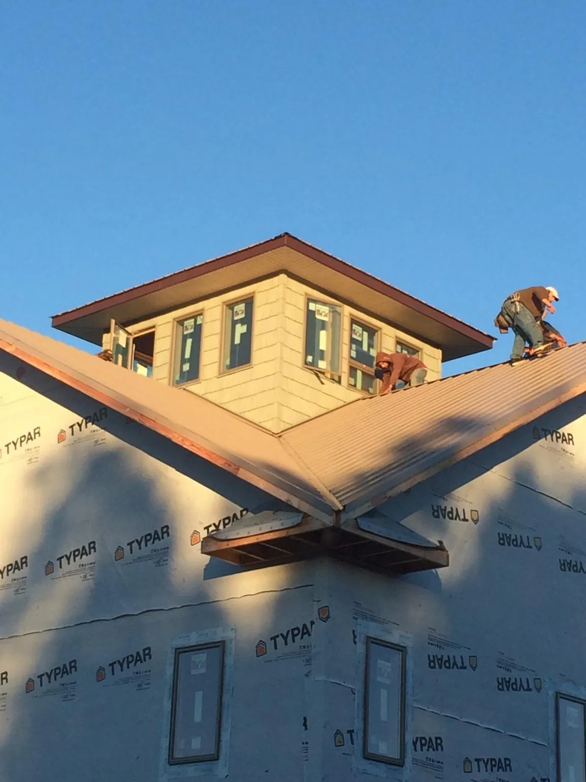 Roofers working around a rooftop cupola on a new metal roof at sunset — Roof Waterproofing in Belle Center by Roofing Brothers